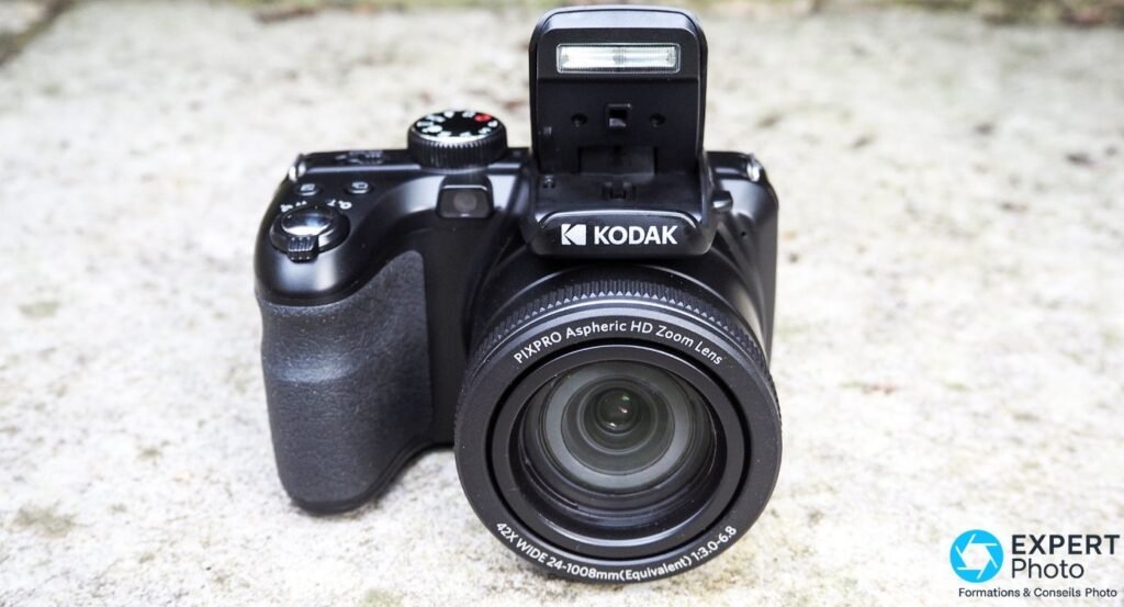 Kodak PIXPRO AZ425 profil gauche sur pierre, zoom 42x IS Wide Angle sorti, flash ouvert, bouton OPEN visible sur coque