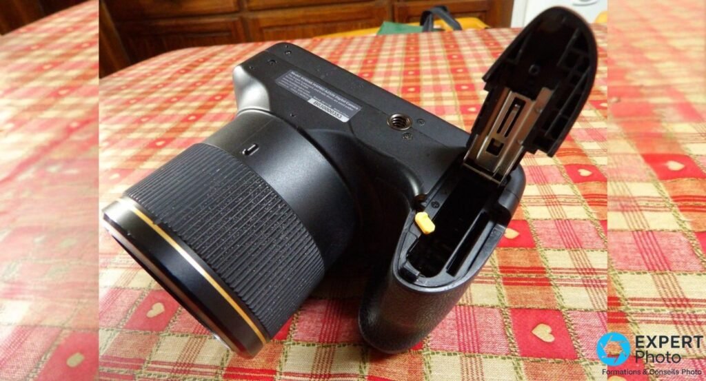 Kodak PIXPRO AZ526 vu de dessous, trappe du compartiment batterie LB-060 et carte SD ouverte, filetage trépied visible.