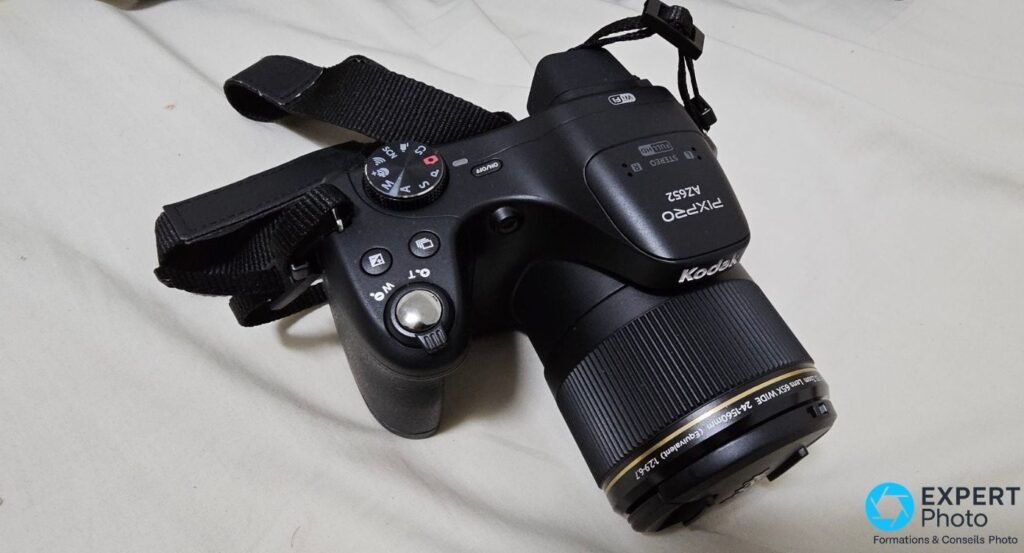 Kodak PIXPRO AZ652 en vue trois quarts arrière gauche, molette PASM visible, inscription objectif 24-1560 mm sur barillet