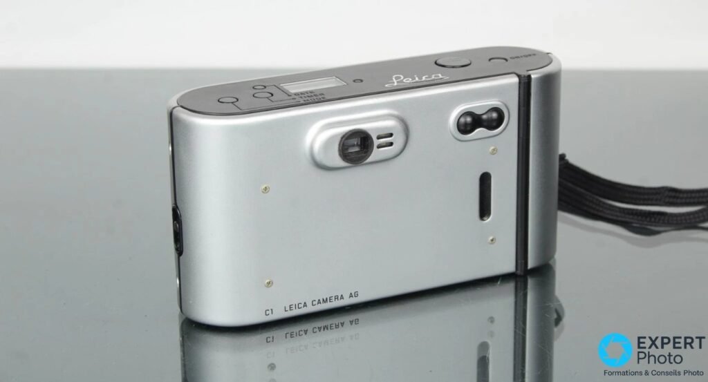 Leica C1 argentique vu de trois quarts arrière, commandes date timer mode et viseur optique visibles