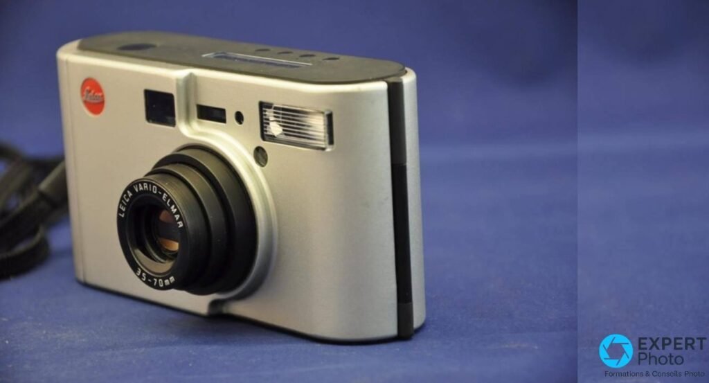 Leica C2 vu de trois quarts avec objectif Leica Vario-Elmar 35-70 mm déployé en position télé et flash intégré.