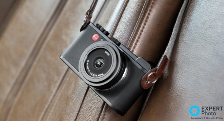 Leica CL avec objectif Elmarit-TL 18mm f/2.8 ASPH posé sur un fauteuil en cuir beige avec lanière en cuir brune