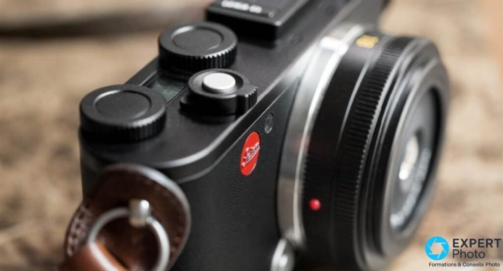 Gros plan sur le top plate du Leica CL, deux molettes crantées noires, déclencheur argent, logo Leica, lanière cuir