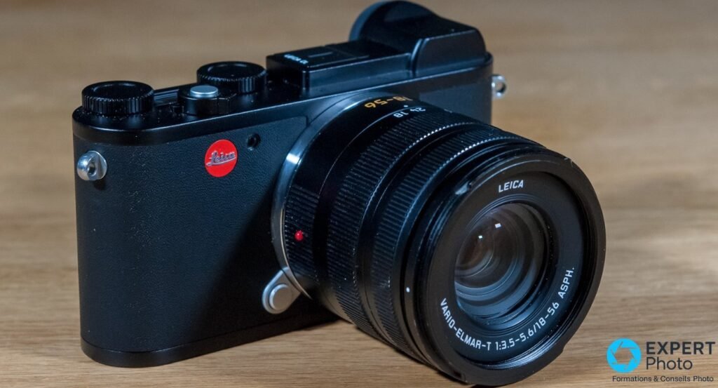 Leica CL avec objectif Vario-Elmar-T 18-56mm f/3.5-5.6 ASPH posé sur une table en bois, vue trois-quarts face