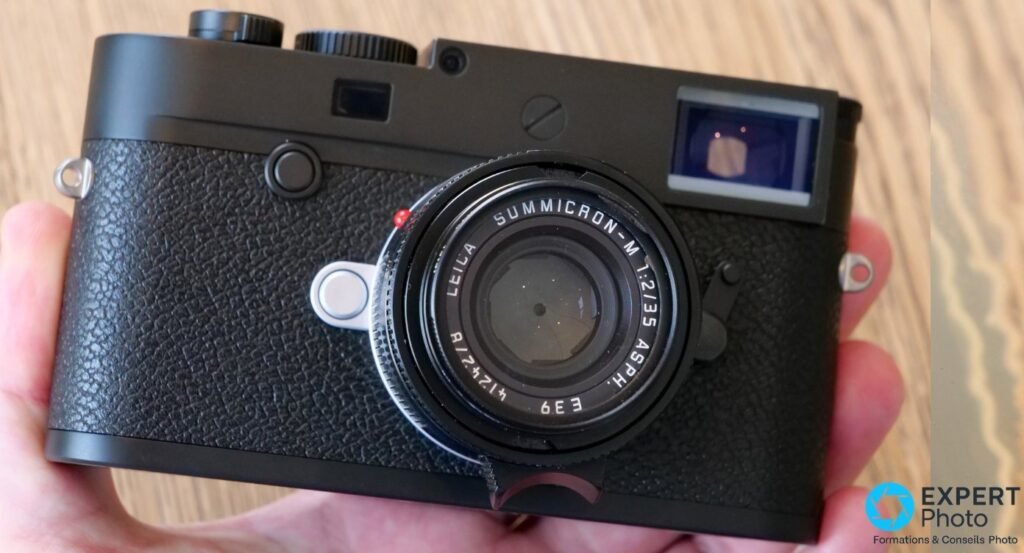 Leica M10-P noir avec Summicron-M 35 mm f/2 ASPH monté, tenu dans une main, vue de face légèrement en plongée. 