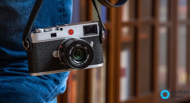 Leica M11 argenté avec APO-Summicron-M 35 mm f/2 ASPH suspendu à une lanière en cuir noir, sur fond jeans bleu.