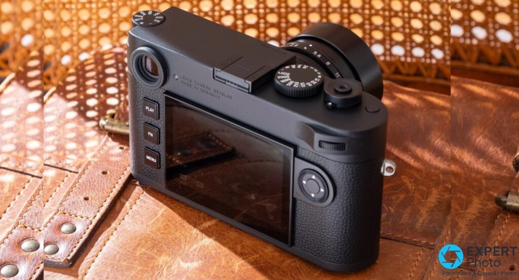 Leica M11 Monochrom vu de dos en trois quarts, boutons PLAY/FN/MENU et écran tactile en veille, cuir brun.