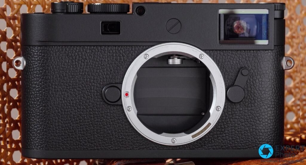 Leica M11 Monochrom de face sans objectif, monture M ouverte avec point rouge d'alignement, fond cannage.