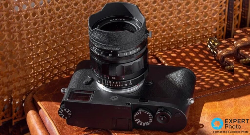  Leica M11 Monochrom vu de dessus, Voigtländer Nokton 35 mm avec pare-soleil tressé monté, posé sur cuir brun.
