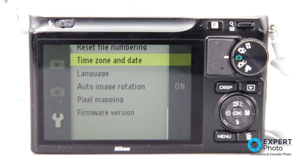 Écran arrière du Nikon 1 J2 affichant le menu système avec Time zone and date, Language et Firmware version