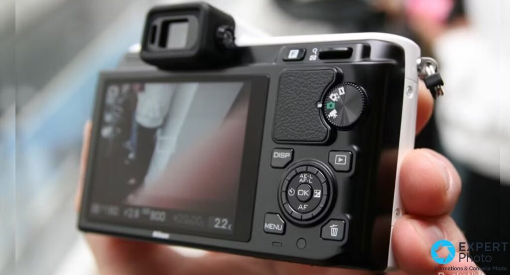 Nikon 1 V1 vu de dos, écran LCD 3 pouces, viseur électronique intégré, molette de modes et touches DISP, MENU, OK