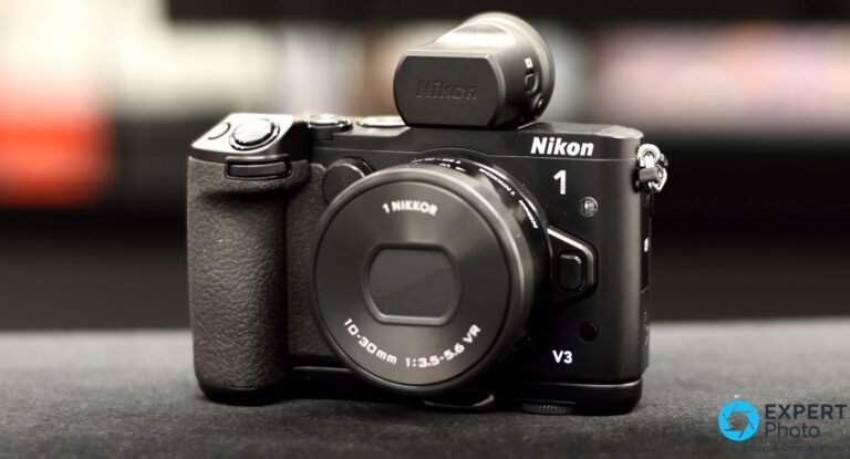 Nikon 1 V3 noir avec viseur DF-N1000 et objectif 1 NIKKOR 10-30 mm VR, vue 3/4 avant sur fond sombre
