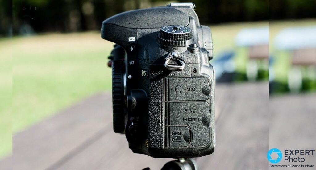 Nikon D600 profil droit, couvercles caoutchouc fermés des ports MIC, HDMI et USB en haut, GPS en bas, badge FX visible.