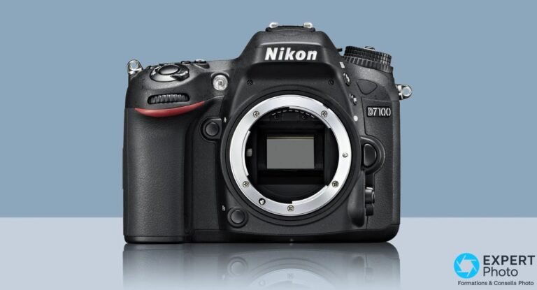 Nikon D7100 boîtier nu de face, monture Nikon F argentée ouverte avec capteur APS-C visible, fond bleu