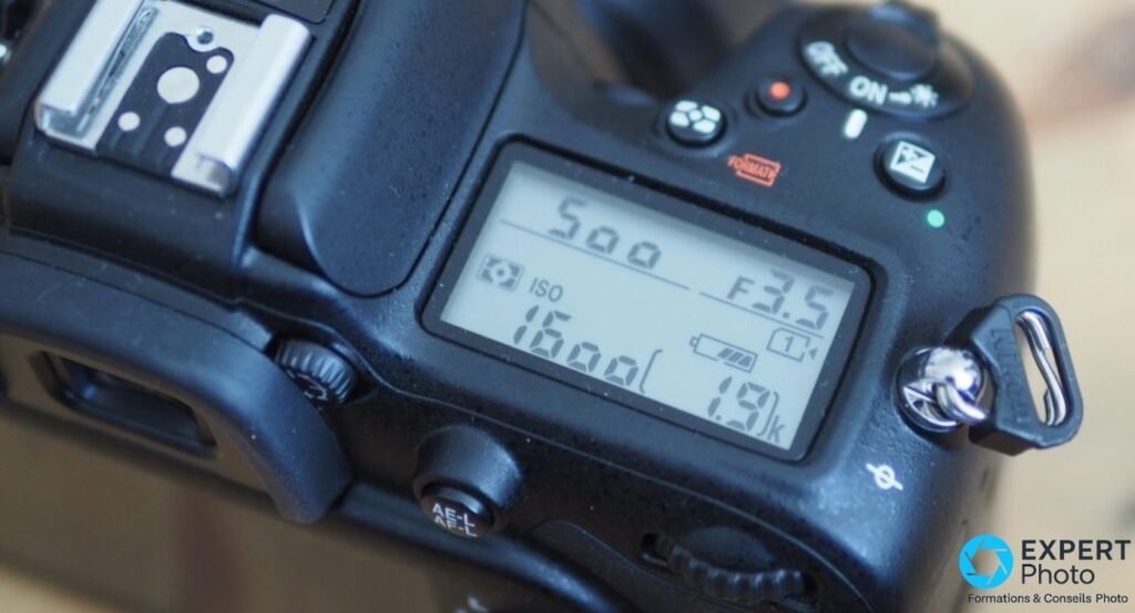 Gros plan sur l'écran LCD supérieur du Nikon D7200 affichant ISO 1600, ouverture F3.5, vitesse 500 et 1,9k images restantes 