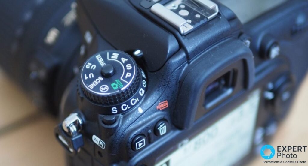 Nikon D7200 vu de dessus, gros plan sur la molette de mode avec positions M, A, S, P, AUTO et griffe flash