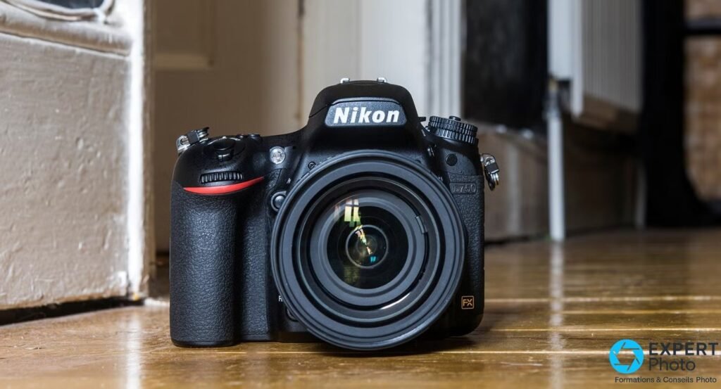 Nikon D750 de face sur parquet, logo Nikon et inscription D750 visibles, badge FX, grip prononcé, objectif zoom monté 