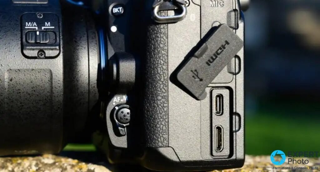 Nikon D780 flanc gauche, cache HDMI ouvert, deux ports USB visibles, commutateur AF-M objectif et prise MIC en haut