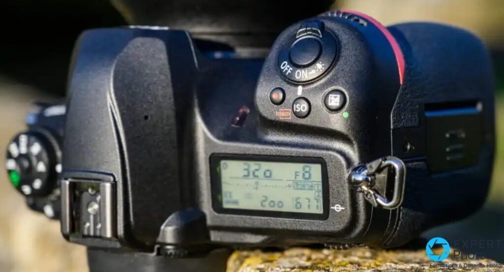 Nikon D780 vue de dessus, écran LCD affichant vitesse 320 et ouverture F8, bouton ISO, sabot flash et commutateur ON/OFF