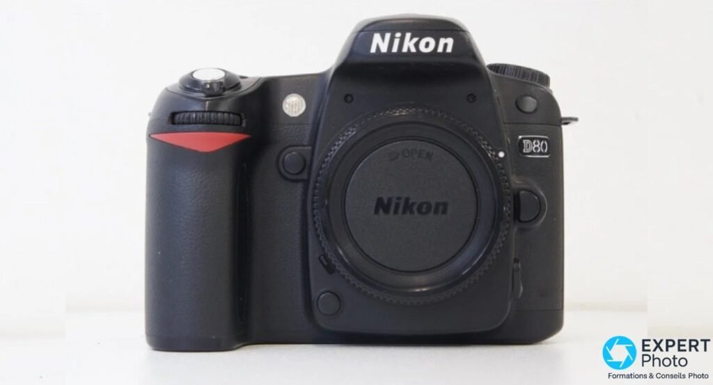 Nikon D80 reflex noir vu de face, boîtier nu avec bouchon de baïonnette monté, logo Nikon visible sur le pentaprisme