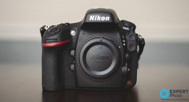 Nikon D800 de face avec bouchon de monture F-mount Nikon, badge FX orange visible, fond gris uniforme