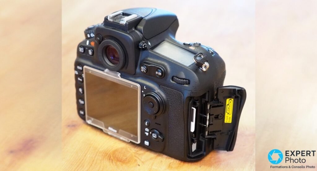 Nikon D810A vu de derrière, trappe double slot carte mémoire ouverte révélant logements CF et SD, écran LCD visible 