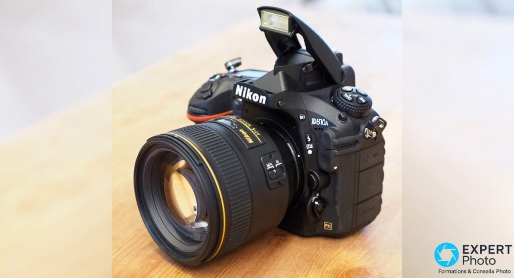 Nikon D810A en vue trois quarts avant, flash intégré relevé, objectif Nikon monté, logo D810a et badge FX visibles