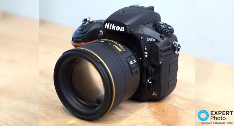 Nikon D810A posé sur table en vue trois quarts avant, objectif Nikon lumineux monté, badge FX et logo visibles