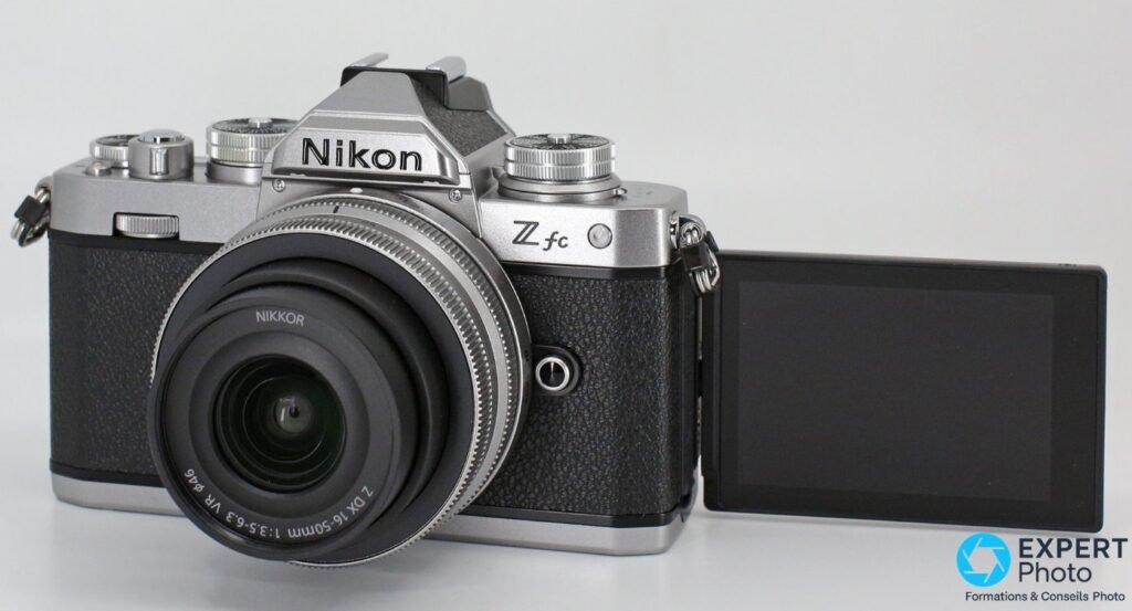 Nikon Z fc argenté avec NIKKOR Z DX 16-50 mm, écran tactile sur rotule déployé vers le côté droit, fond blanc.