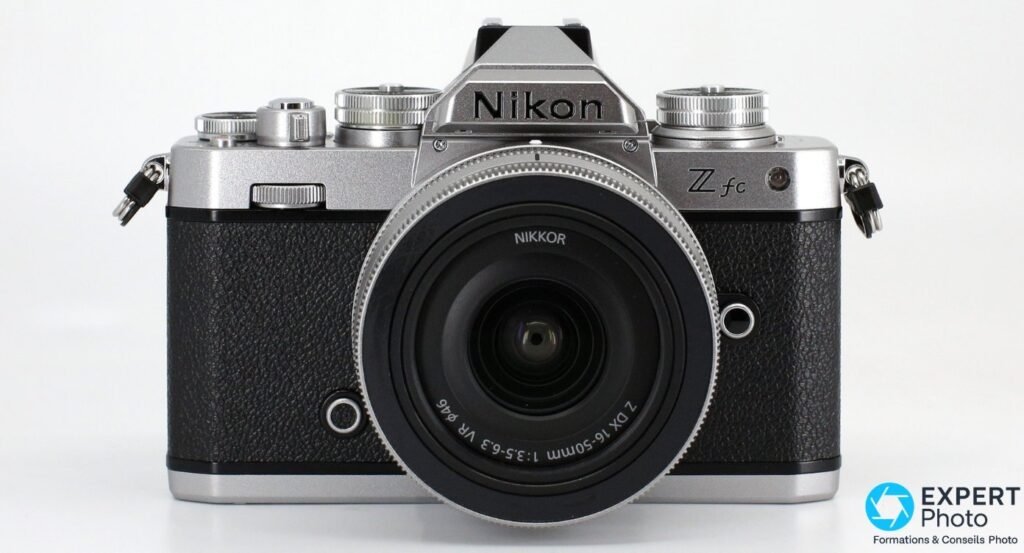 Nikon Z fc de face symétrique, NIKKOR Z DX 16-50 mm VR rétracté au centre, fond studio blanc.