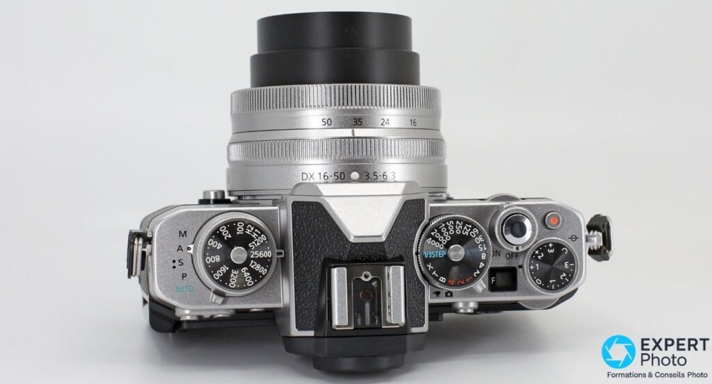 Nikon Z fc en plongée verticale, molettes ISO, vitesse 1/3 STEP, correction d'exposition et zoom 16-50 mm visibles. 