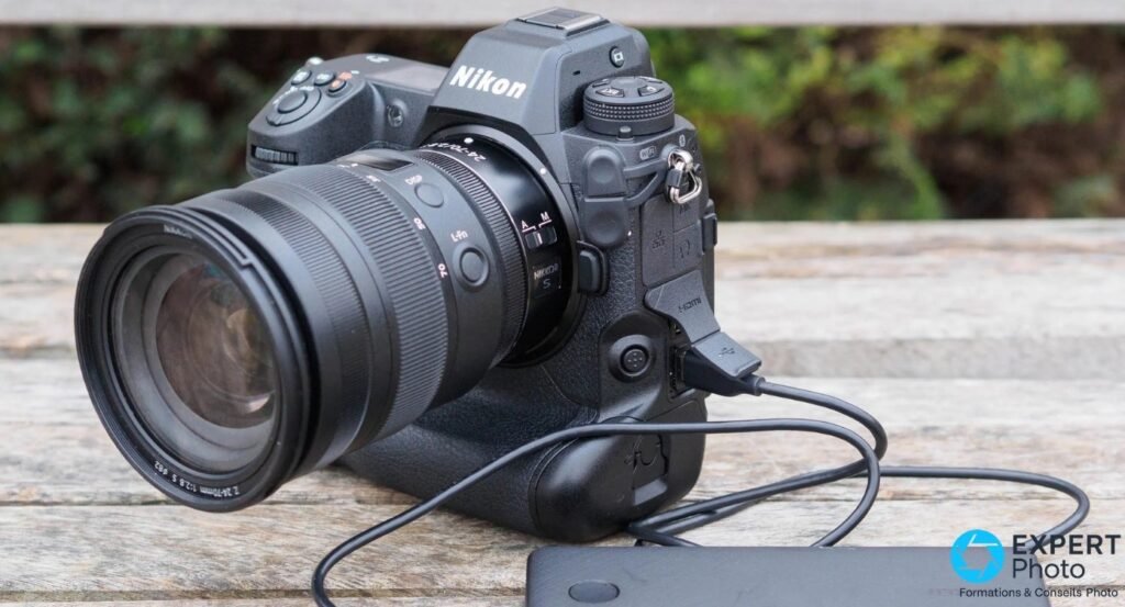 Nikon Z9 avec objectif Nikkor Z 24-70 f/2.8 S posé sur table en bois, câble USB-C branché à une batterie externe 