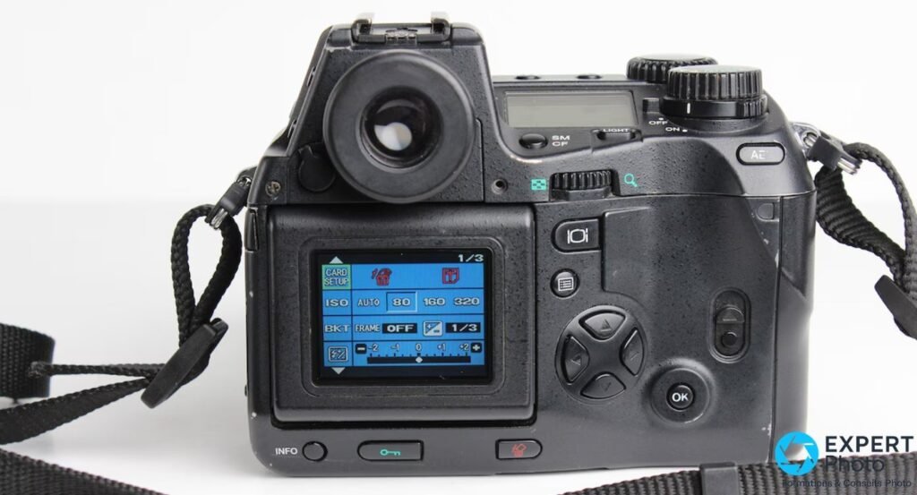 Dos de l'Olympus E-10 avec viseur TTL, pad directionnel et écran LCD affichant un menu bleu CARD SETUP et ISO 80 à 320.