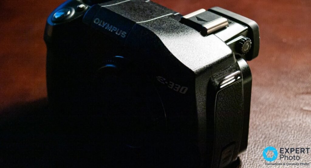 Olympus E-330 en gros plan de profil, logos OLYMPUS et E-330 en relief sur le sommet, griffe flash visible