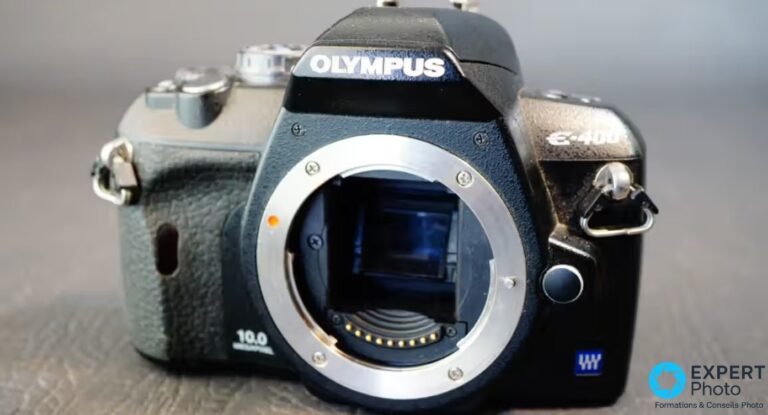 Olympus E-400 de face, boîtier nu, monture Four Thirds ouverte, logo OLYMPUS et marquage 10.0 MEGAPIXEL lisibles.