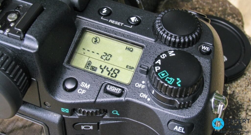 Olympus E-20 en gros plan sur l'écran LCD supérieur affichant CF et 448 poses, molette de modes M S A P visible