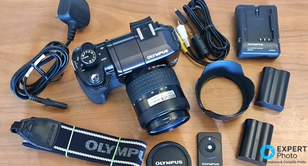 Kit Olympus E-300 vu de dessus : boîtier avec 14-45mm, chargeur BCM-2, deux batteries, pare-soleil, télécommande.