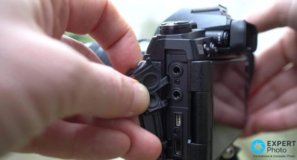Connecteurs latéraux de l'Olympus OM-D E-M1 Mark III avec trappe ouverte : prises jack, HDMI et USB visibles.
