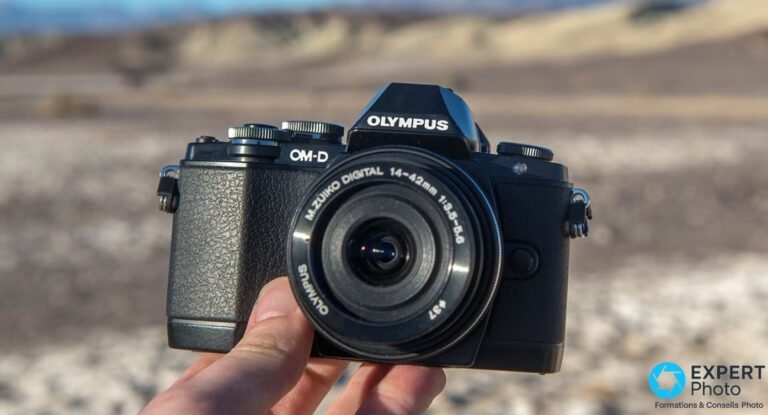 Boîtier hybride Olympus OM-D E-M10 noir avec zoom M.Zuiko Digital 14-42 mm 1:3.5-5.6 tenu à la main en désert