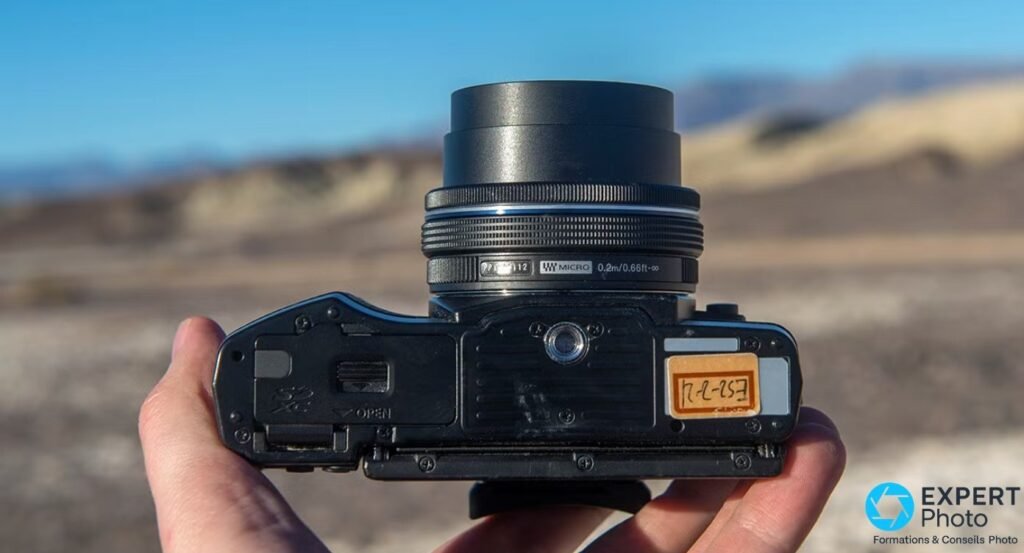 Olympus OM-D E-M10 retourné avec objectif M.Zuiko 14-42 mm EZ, trappe de batterie OPEN et filetage de trépied 