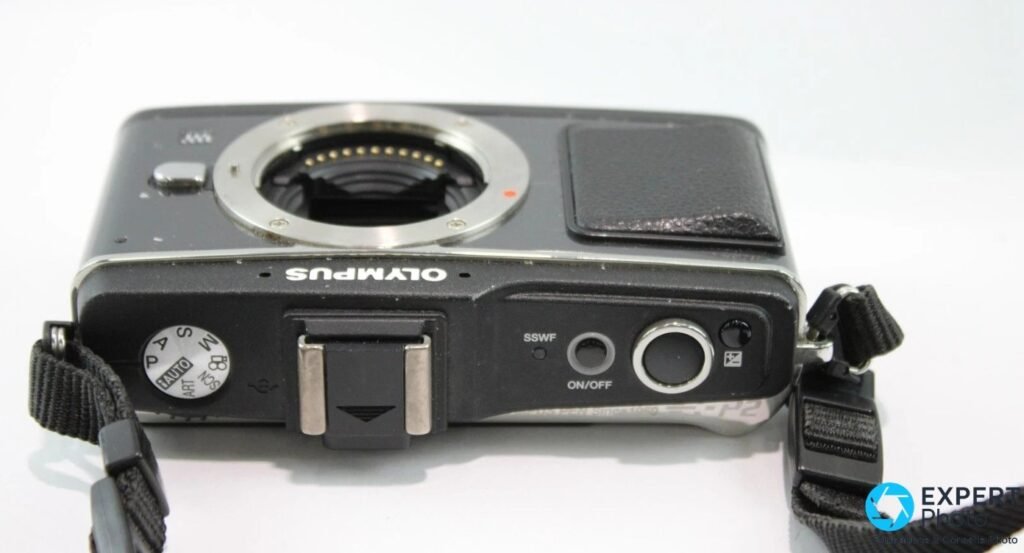 Dessus de l'Olympus PEN E-P2, molette des modes PASM iAUTO SCN ART, déclencheur, bouton ON/OFF et port accessoire fermé.