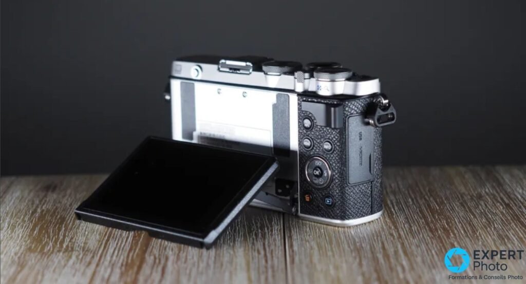 Olympus PEN E-P7 trois quarts arrière, écran inclinable déployé vers le bas, ports USB et HDMI sur le côté droit. 