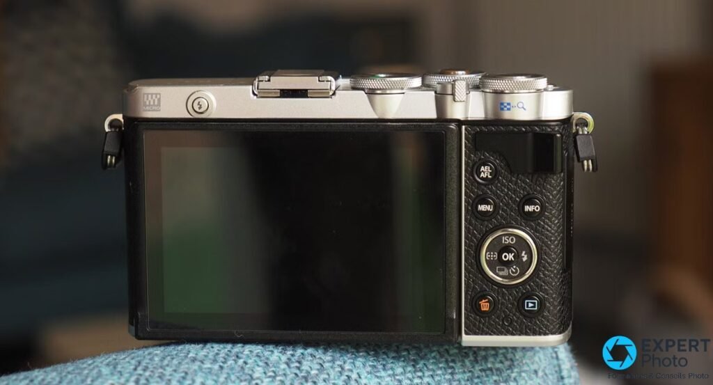 Olympus PEN E-P7 de dos, écran LCD éteint, boutons AEL/AFL, MENU, INFO, molette ISO, griffe porte-accessoire vide.