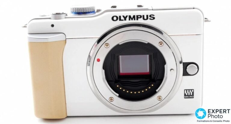 Face avant de l'Olympus PEN E-PL1 blanc sans objectif : logo OLYMPUS, badge MICRO 4/3 et grip beige.