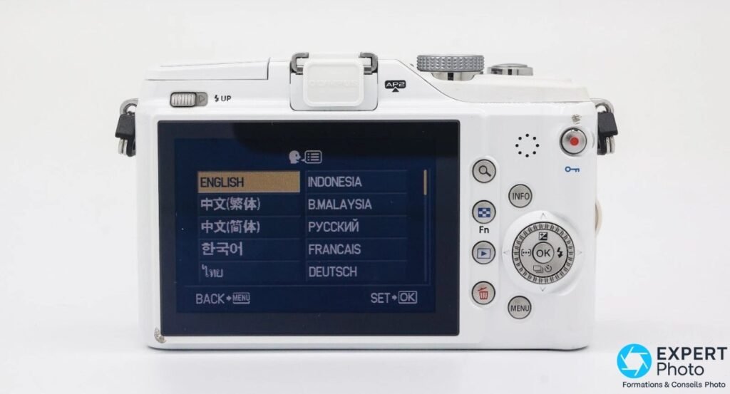Olympus PEN E-PL2 vu de dos, écran LCD affichant menu langues, molette de navigation et boutons