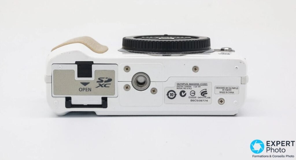 Olympus PEN E-PL2 vu du dessous, trappe SDXC, filetage trépied et étiquette modèle E-PL2 