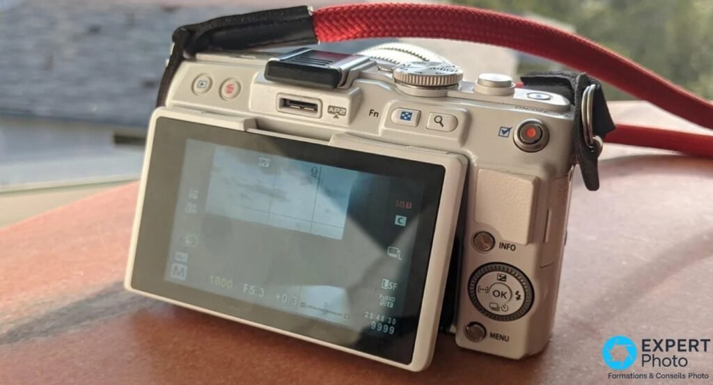 Dos de l'Olympus PEN E-PL6 blanc, écran LCD incliné affichant l'interface de prise de vue en mode manuel
