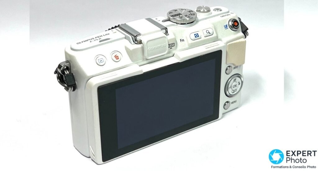 Olympus PEN E-PL6 blanc vu de dos en trois quarts gauche, marquage PEN Lite E-PL6 lisible sur le dessus du boîtier