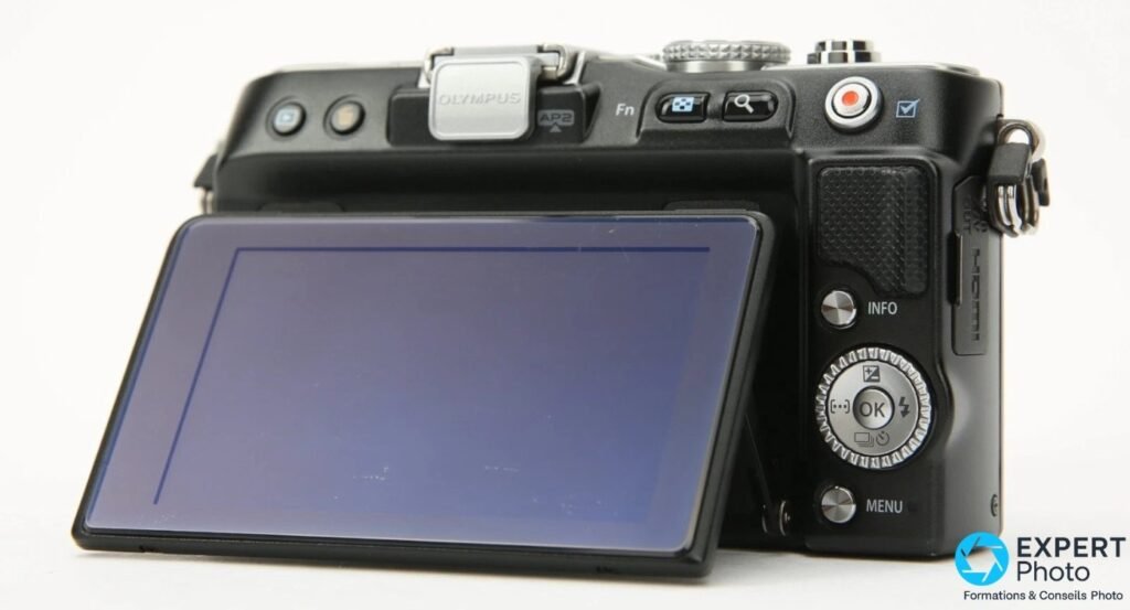 Boîtier Olympus PEN E-PL3 noir vu de dos trois-quarts, écran LCD inclinable déployé, flash FL-LM1 monté sur la griffe.