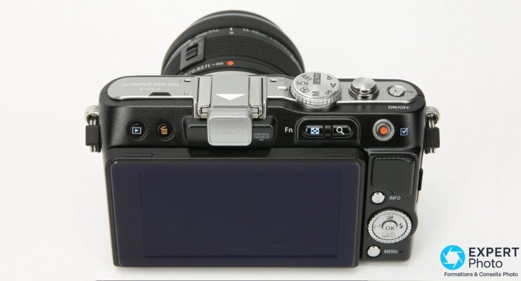 Dessus de l'Olympus PEN E-PL3 : gravure OLYMPUS PEN Lite E-PL3, molette de modes PASM et flash FL-LM1 visibles. 